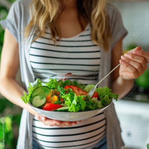 Young pregnant woman eating fresh vegetables salad
