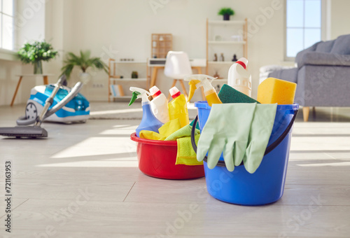 Close up photo of various cleaning tools items and supplies standing on the living room floor. Buckets with rags and bottles of detergent. Cleaning service and housekeeping work concept.
