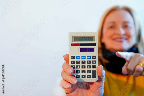 A senior woman showing the camera a white calculator with copy space photo
