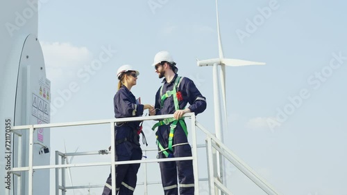 Professional technician mand and woman workers stand and discuss about work and stay in base of windmill or wind turbine in area of green power plant. photo