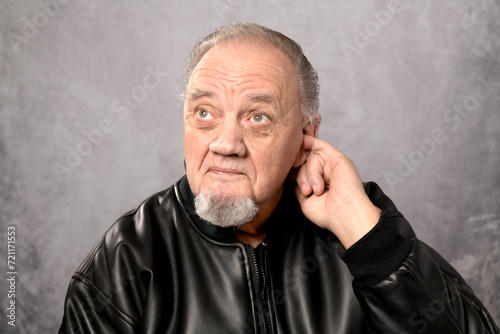 portrait vieil homme doigt dans oreille sur fond gris photo