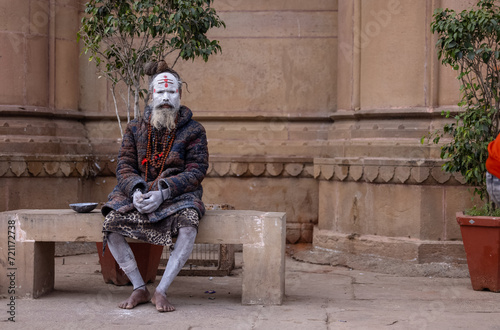 Portrait of an old holy sadhu baba with ash on his face sitting on ghats near river ganges. 