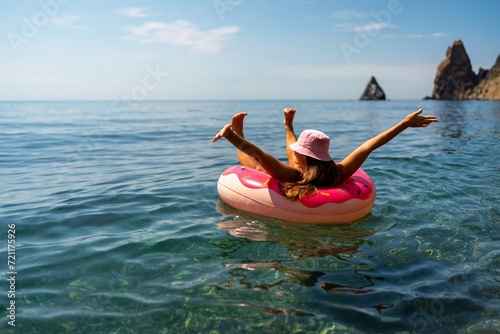 Summer vacation woman in hat floats on an inflatable donut mattress. Happy woman relaxing and enjoying family summer travel holidays travel on the sea. © svetograph