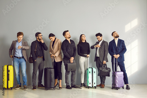 European business people in suits with bags and suitcases line up while standing inside the airport and waiting their turn to go to the check-in counters or boarding gate. Travelling by plane concept
