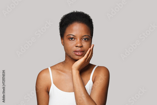 Attractive healthy african american woman with clear fresh dark skin posing on gray background, fashion beauty portrait