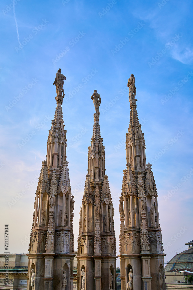 Spires with statues against a clear blue evening sky at the Duomo di Milano (Milan Cathedral) in Milan, Italy