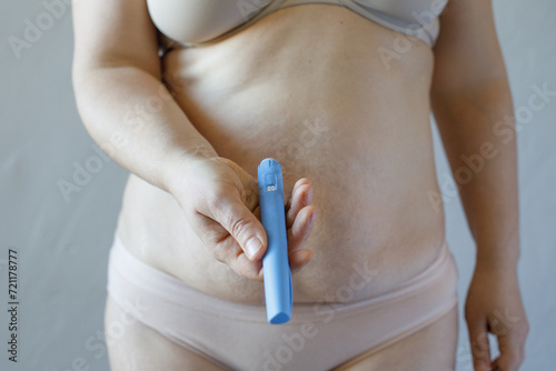 Woman body closeup with Semaglutide Injection pen or insulin cartridge pen. Medical equipment for diabetes patient. Diabetes and weight loss concept.