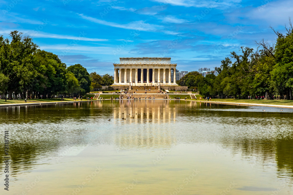 The Abraham Lincoln Memorial Pantheon reflected in the reflecting pool pond under a clear blue sky on the National Mall in Washington DC, USA.