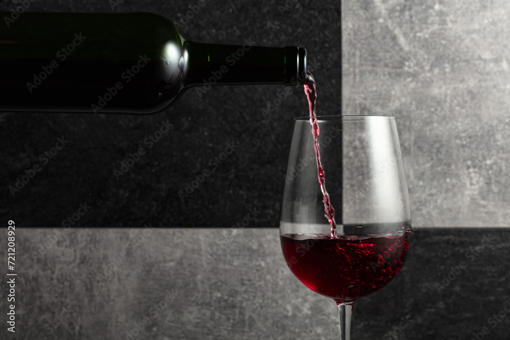 Fototapeta premium Red wine is poured from the bottle into a glass.