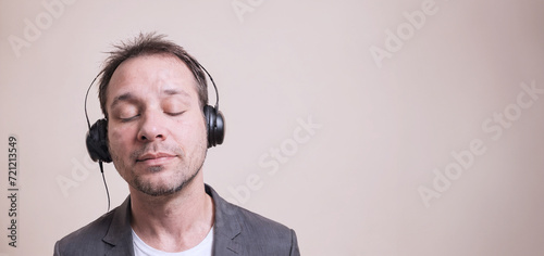 giovane uomo in abbigliamento casual con cuffie che ascolta concentrato musica, occhi chiusi, primo piano photo