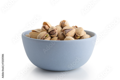 salted pistachios in blue bowl isolated on white background