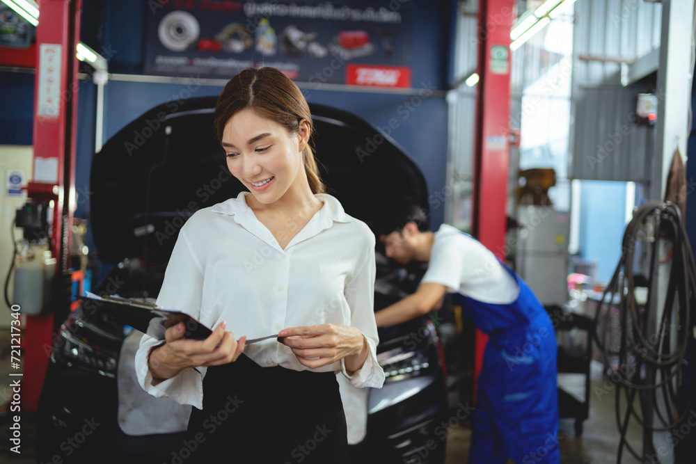 asian female customer checks maintenance work with auto mechanic in auto repair shop.