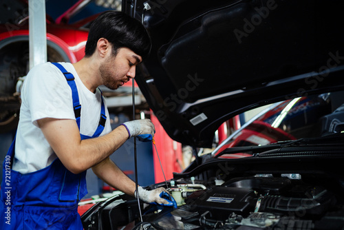 Asian auto mechanic working on car engine. Think about repairs and customer service. Working on the engine in the garage automobile car concept