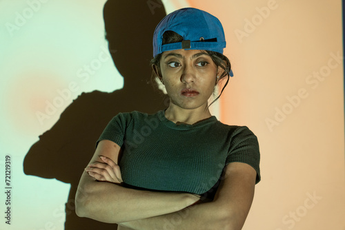 a multi-racial girl with a blue hat and a black T-shirt looking in the aggressive way with high attitude © oybekostanov