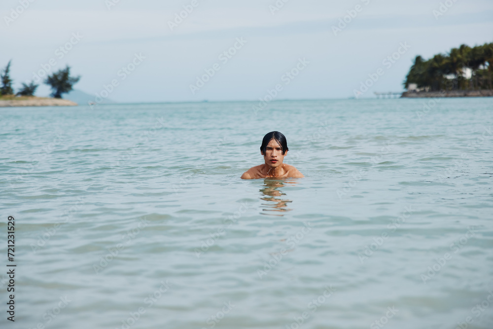Swimming Asian Man in Tropical Beach Water: Vacation Bliss