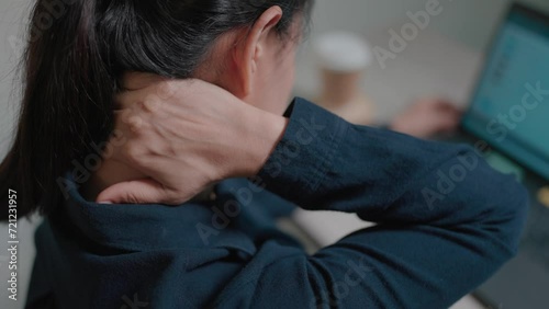 Tired female guest woman has neck pain working at computer sitting on sofa in office at night