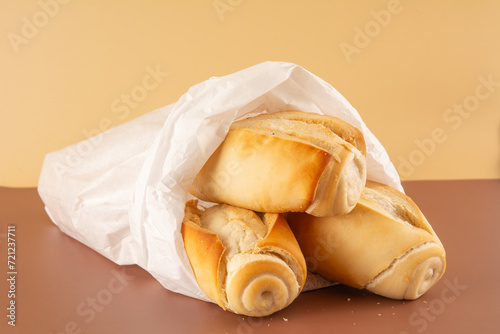 Fresh baked flour bread in paper bag in brown and beige background in front view angle with empty blank space