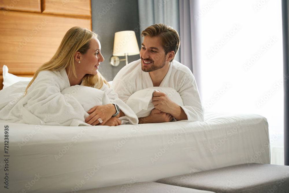 Woman and a man communicate while lying on large bed Woman and a man communicate while lying on large bed