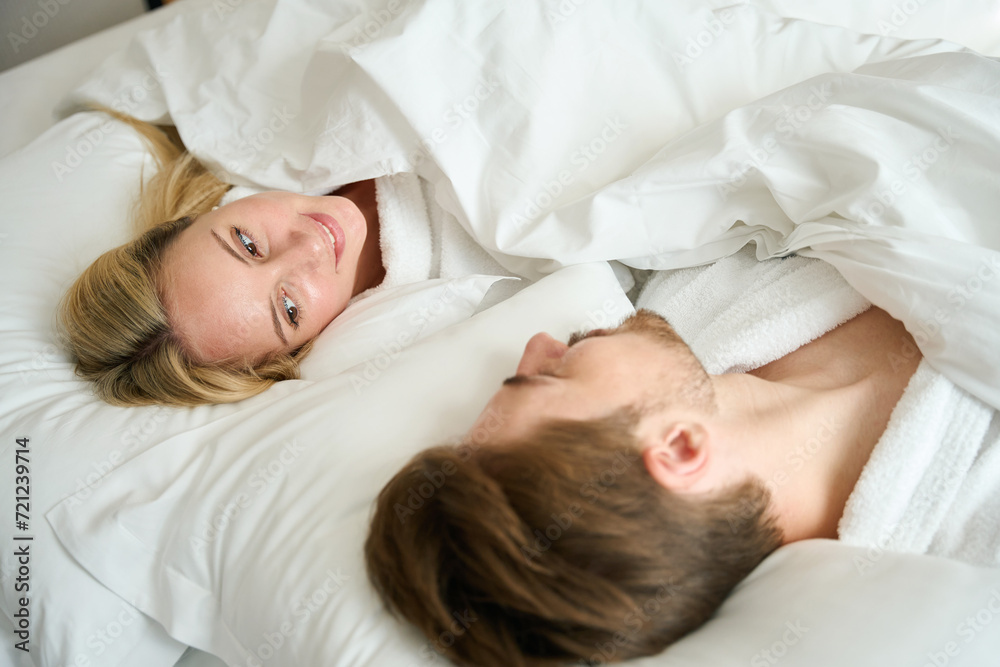 Man and woman are lying in bed in hotel room