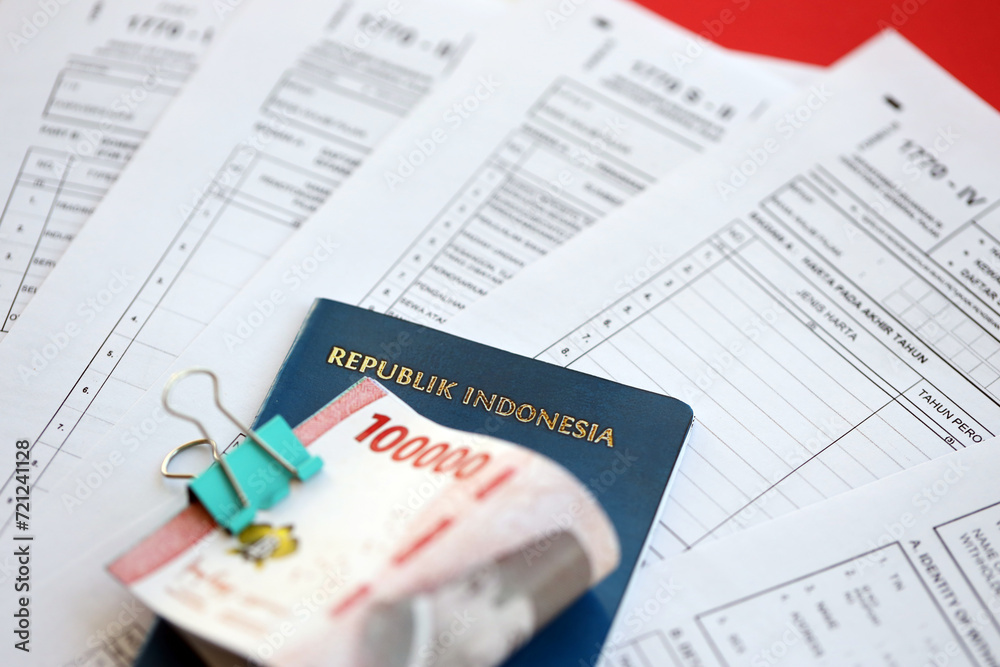Indonesian tax forms 1770 Individual Income Tax Return and money with passport on table close up