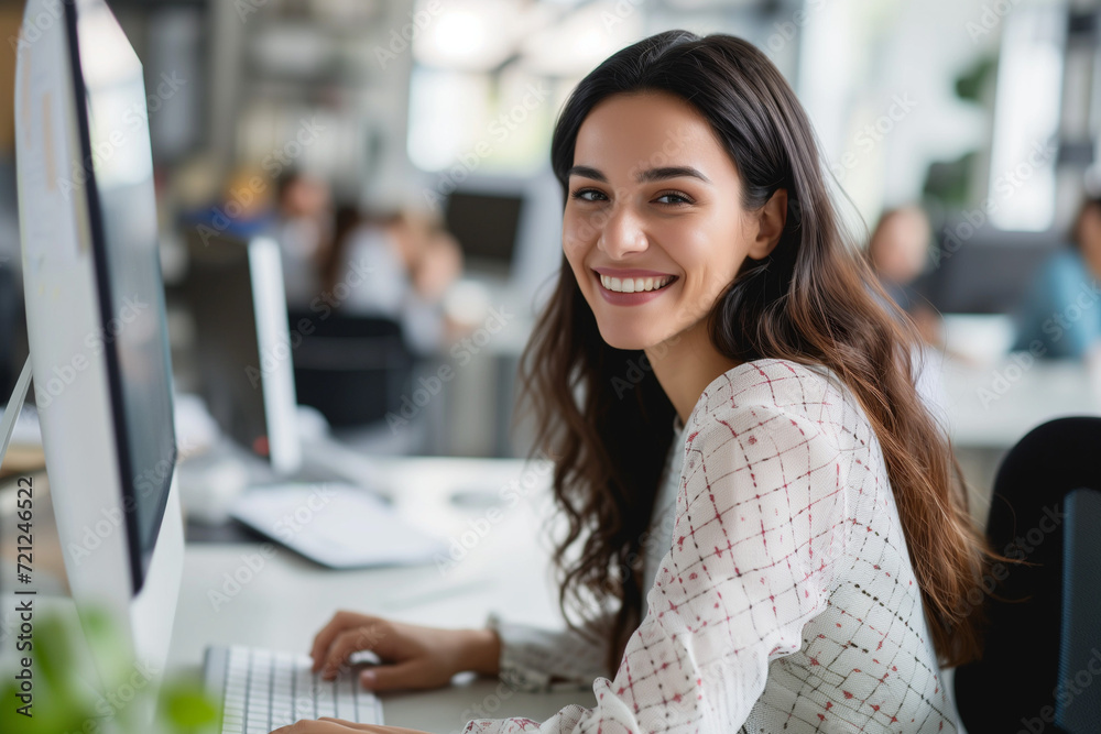 Portrait of Enthusiastic Hispanic Young Woman Working on Computer in a Modern Bright Office. Confident Human Resources Agent Smiling Happily While Collaborating Online with Colleagues Portrait of Enthusiastic Hispanic Young Woman Working on Computer in a Modern Bright Office. Confident Human Resources Agent Smiling Happily While Collaborating Online with Colleagues