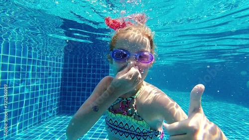 little girl deftly swim underwater in pool