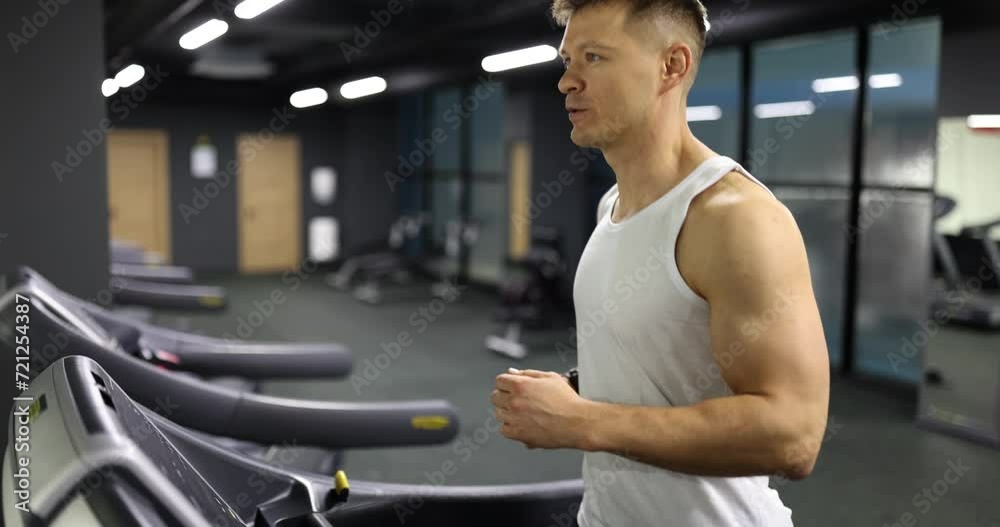 Young man in sportswear runs on treadmill in gym. Healthy sports fitness Young man in sportswear runs on treadmill in gym. Healthy sports fitness