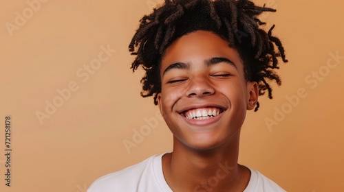 Happy young African American gen z guy winking isolated on beige background. Playful ethnic teen student, cool curly generation z teenager smiling