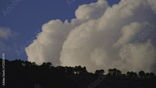 Huge white clouds are moving fast in the mountains.