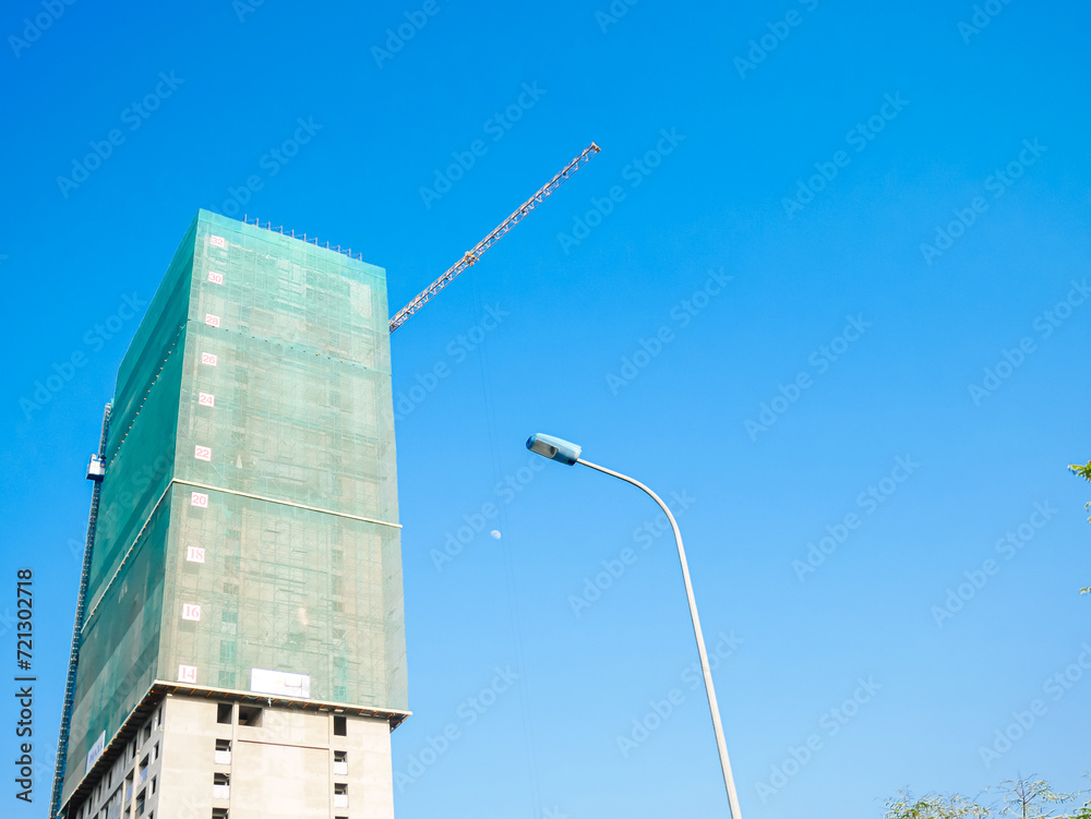 Street light post looking up high rise condo apartment under construction green safety nets netting prevents dropping of building materials or work staff in Hanoi, Vietnam, urban housing Street light post looking up high rise condo apartment under construction green safety nets netting prevents dropping of building materials or work staff in Hanoi, Vietnam, urban housing