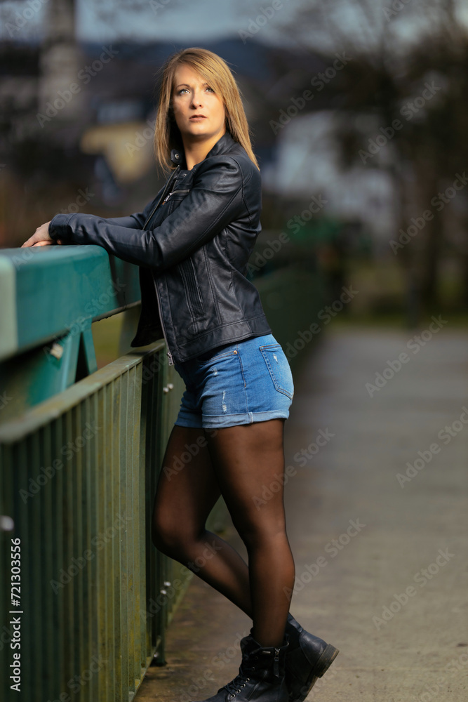 Young woman in her thirties photographed in portraits on a bridge with flash.
