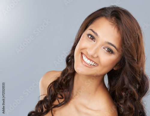 Portrait, beauty and hair of happy woman in makeup in studio isolated on a grey background. Face, smile or curly hairstyle of model in cosmetics, hairdresser and salon treatment for care of skin glow