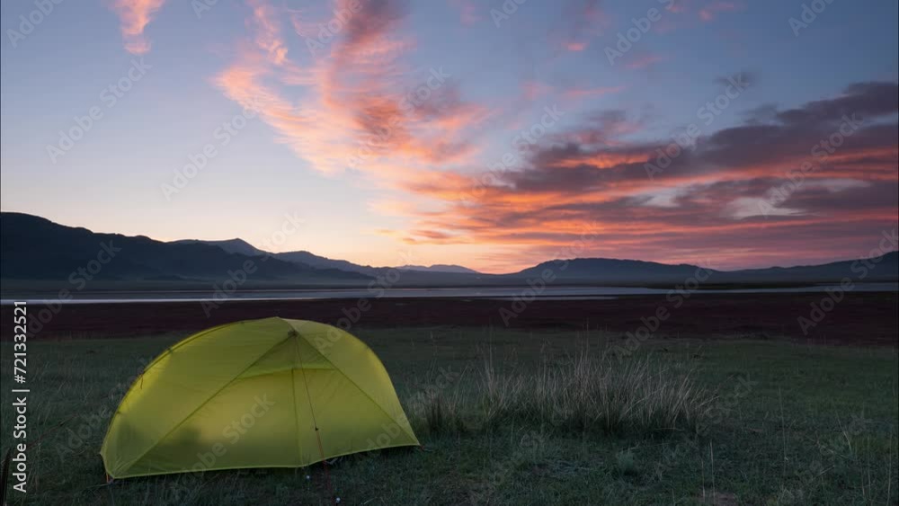 Late evening outdoors with a tent and a view of a mountain lake. Beautiful red clouds are illuminated by the setting sun. Lake Tuzkol. Kazakhstan. Time lapse Late evening outdoors with a tent and a view of a mountain lake. Beautiful red clouds are illuminated by the setting sun. Lake Tuzkol. Kazakhstan. Time lapse