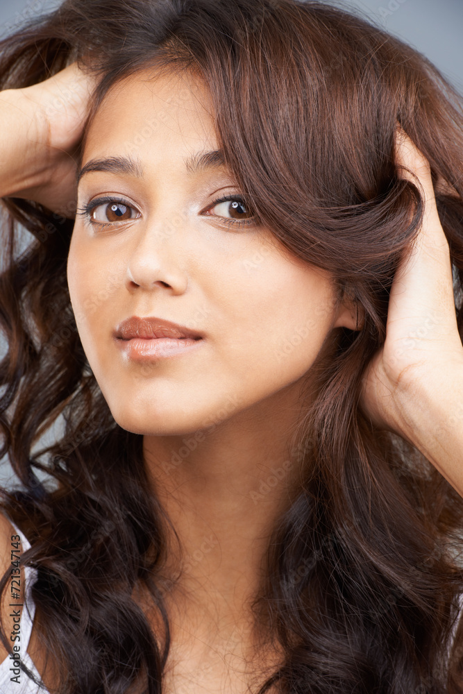Portrait, salon and hair with indian woman in studio on gray background for aesthetic, shampoo or wellness. Face, beauty or skincare and confident young person with treatment for curly haircare Portrait, salon and hair with indian woman in studio on gray background for aesthetic, shampoo or wellness. Face, beauty or skincare and confident young person with treatment for curly haircare
