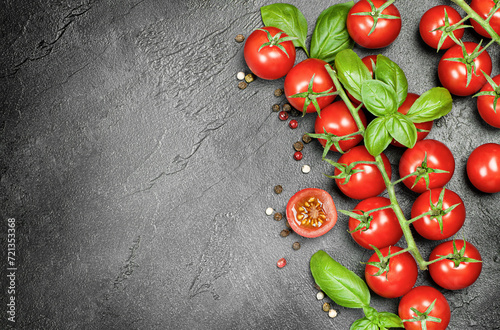 cherry tomatoes, basil and peppercorns on a dark concrete background