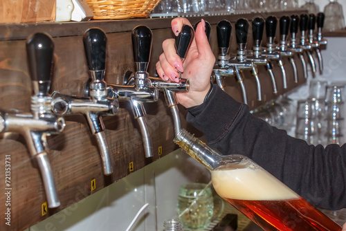 Behind the counter. Women's hands beautifully and easily pour beer into a bottle.