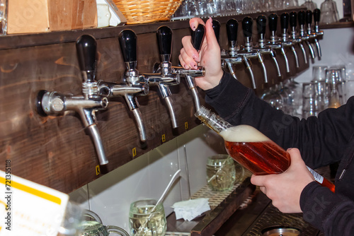 Behind the counter. Women's hands beautifully and easily pour beer into a bottle. photo