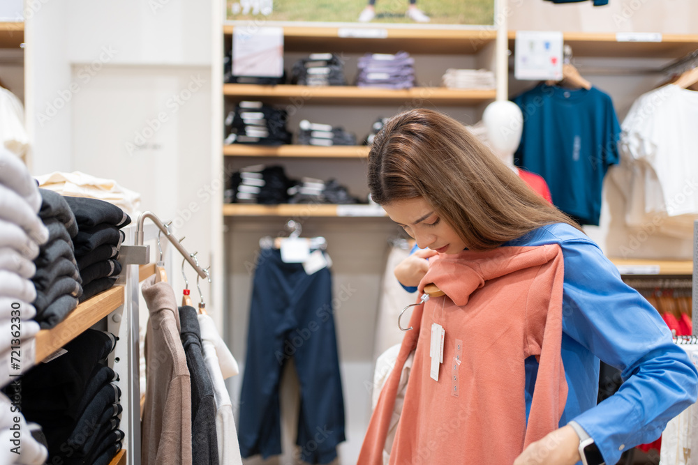 Caucasian or brunette white woman with brown hair shopping shopping for clothes, sweaters, t-shirts in a department store. Caucasian or brunette white woman with brown hair shopping shopping for clothes, sweaters, t-shirts in a department store.