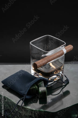 Still life of a glass of whiskey with jade stones for cooling and a cigar © ivancheremisin