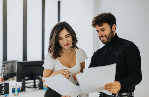 Photography Two colleagues in casual office attire smiling and discussing documents, conveying teamwork and collaboration