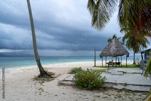 San Blas caribic island shelter hut on beautiful beach with single palm stem in windy weather photo