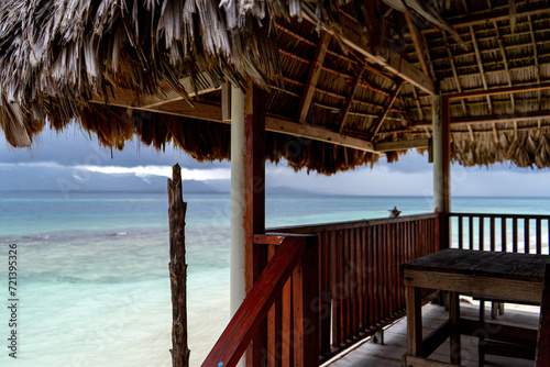 Fototapeta Naklejka Na Ścianę i Meble -  View through balcony of red beach hut with palm roofing on beautiful light blue caribic water