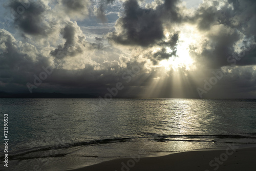 Golden sun rays shining through clouds hitting caribbean water surface
