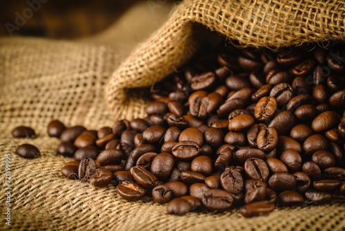 Rich dark coffee beans spilling from a rustic burlap sack © Nico