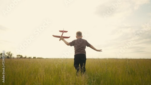 a little boy running in the park on the grass with a toy airplane in his hands. happy family childhood dream concept. a small son runs across the field in the forest with lifestyle a toy photo