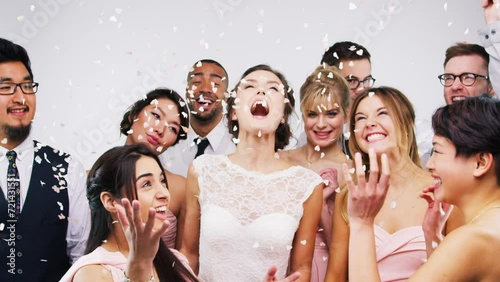 People, wedding and dancing in studio with confetti for celebration, success and party at reception and formal event. Young bride and friends yes, excited and fun for marriage on a white background photo