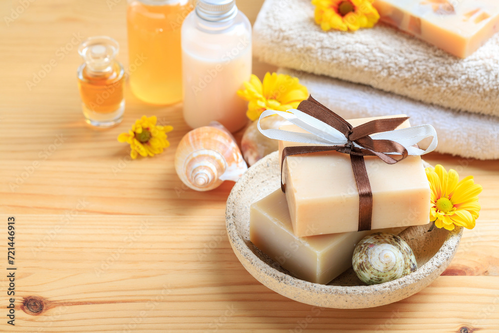 Handmade bars of spa soap collected as a stack. Soft towels and flowers on wooden table, copy space. Handmade bars of spa soap collected as a stack. Soft towels and flowers on wooden table, copy space.