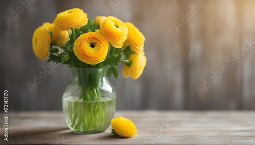 Yellow bouquet of yellow buttercup flowers in a vase on a wooden table  photo