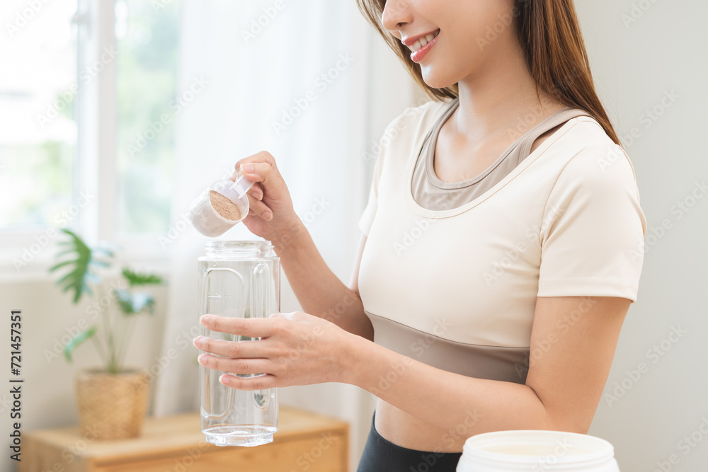 Diet meal replacement for weight loss, asian young woman in sportswear, hand in holding scoop making protein into bottle to shake, drink supplement for muscle after workout at home. Healthy body care. Diet meal replacement for weight loss, asian young woman in sportswear, hand in holding scoop making protein into bottle to shake, drink supplement for muscle after workout at home. Healthy body care.