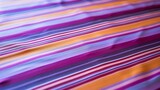 The table cloth has a colorful stripes pattern and is made from smooth purple textile